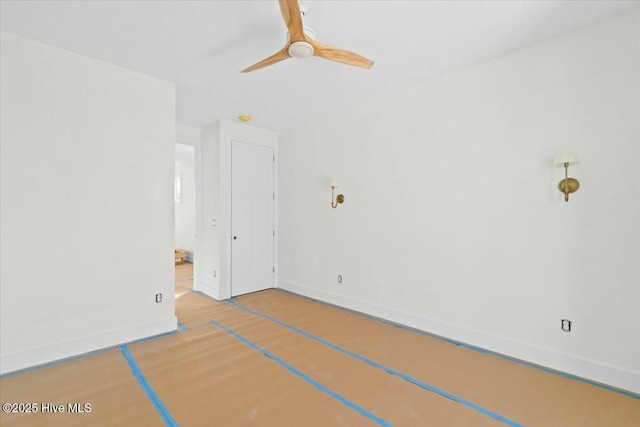 spare room featuring a ceiling fan, wood finished floors, and baseboards