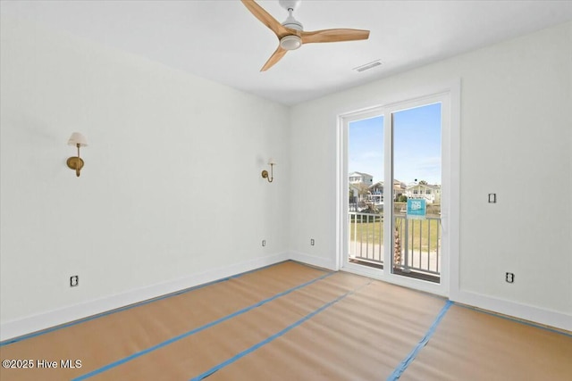 empty room featuring visible vents, a ceiling fan, baseboards, and wood finished floors