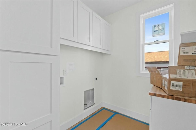 clothes washing area featuring electric dryer hookup, baseboards, and cabinet space
