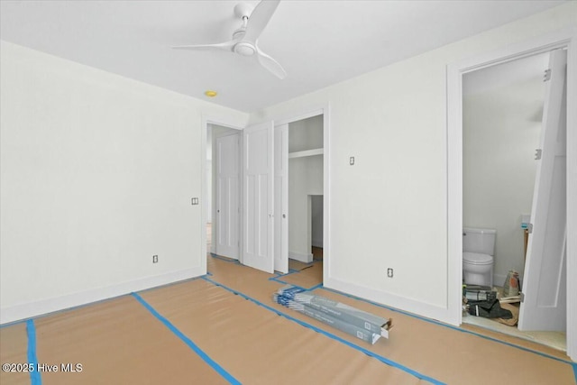 unfurnished bedroom featuring a closet, baseboards, ceiling fan, and ensuite bathroom