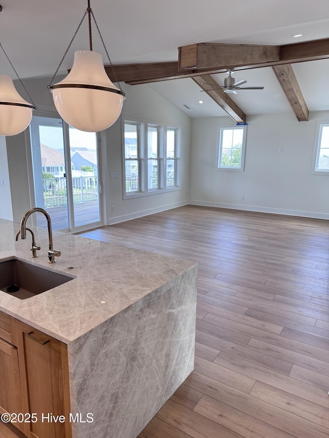 36 Fairmont St, Ocean Isle Beach, NC 28469 - kitchen with a sink, beam ceiling, open floor plan, baseboards, and light stone counters