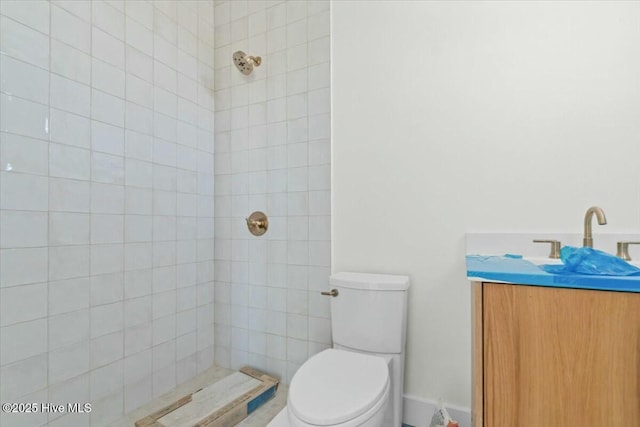 full bath featuring toilet, vanity, and a tile shower