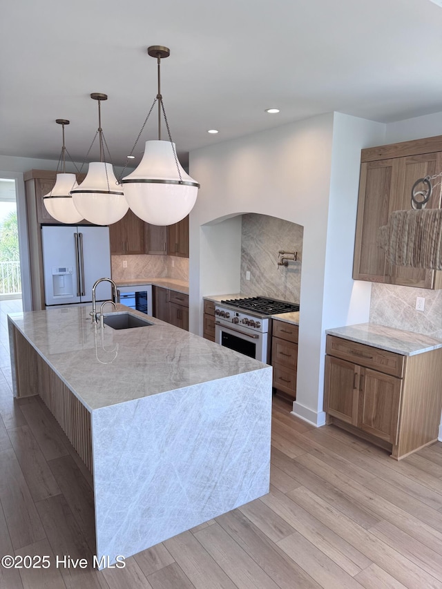 36 Fairmont St, Ocean Isle Beach, NC 28469 - kitchen featuring high end white fridge, a sink, backsplash, light wood-type flooring, and light stone counters
