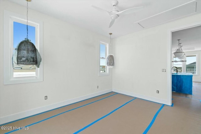 empty room featuring baseboards, attic access, and ceiling fan