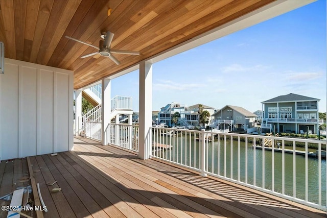wooden terrace with a residential view, a ceiling fan, and a water view