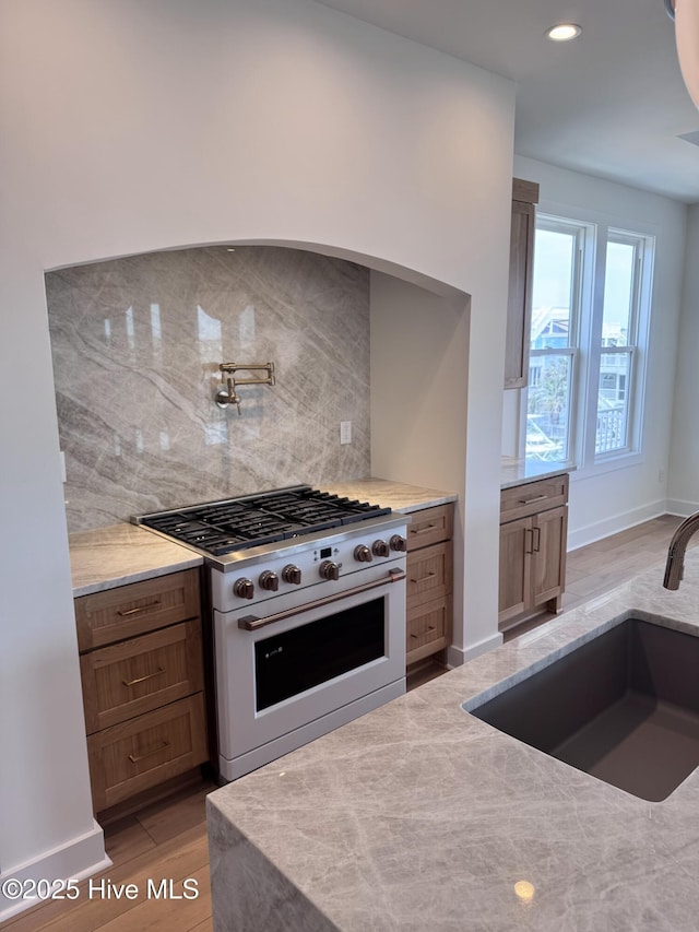 36 Fairmont St, Ocean Isle Beach, NC 28469 - kitchen with high end range, a sink, tasteful backsplash, light wood-style flooring, and light stone counters