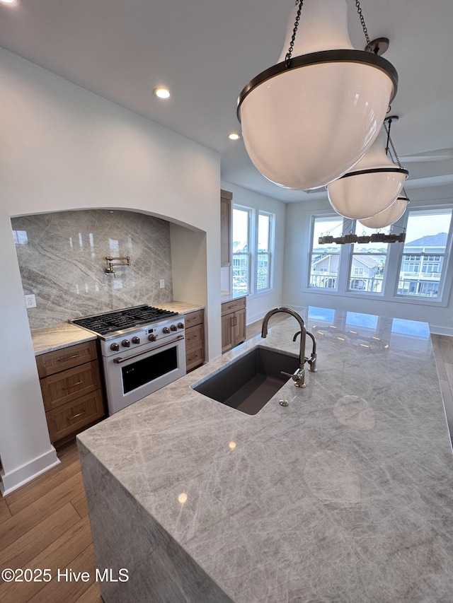 36 Fairmont St, Ocean Isle Beach, NC 28469 - kitchen featuring high end range, a sink, decorative backsplash, light stone countertops, and wood finished floors