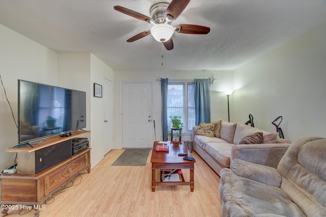 living room featuring ceiling fan, light hardwood / wood-style floors, and a textured ceiling