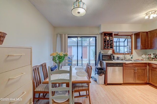 kitchen featuring dishwasher, sink, a textured ceiling, and light hardwood / wood-style flooring