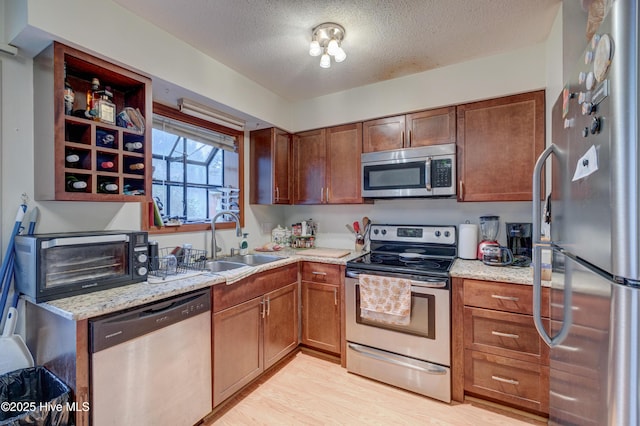 kitchen featuring light stone counters, sink, light hardwood / wood-style flooring, and stainless steel appliances