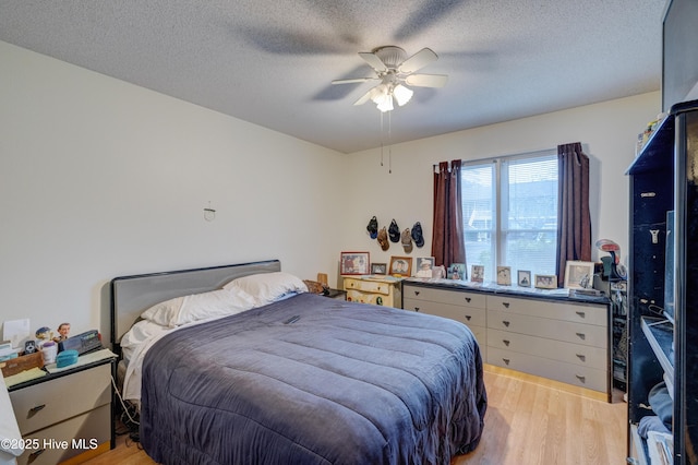 bedroom with ceiling fan, a textured ceiling, and light hardwood / wood-style flooring