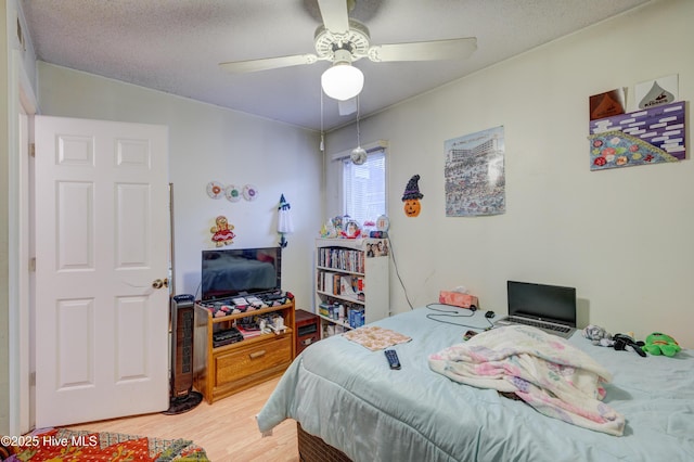 bedroom with ceiling fan, wood-type flooring, and a textured ceiling