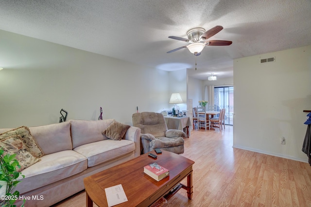 living room with a textured ceiling, light hardwood / wood-style floors, and ceiling fan