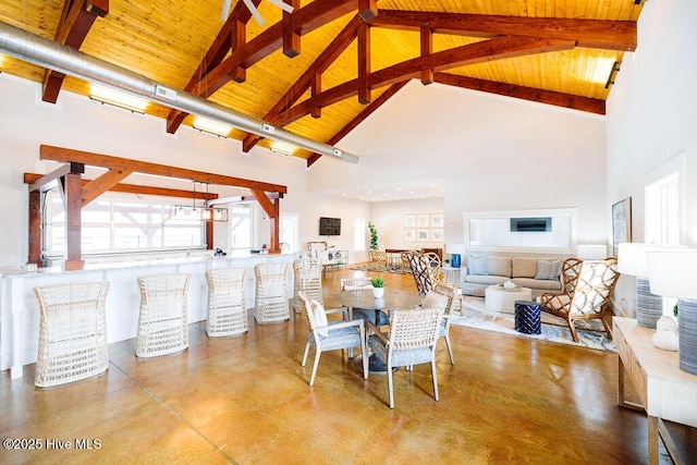 dining space with wooden ceiling, beamed ceiling, finished concrete flooring, and high vaulted ceiling