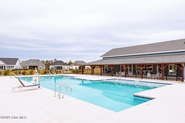 community pool with a patio area and fence