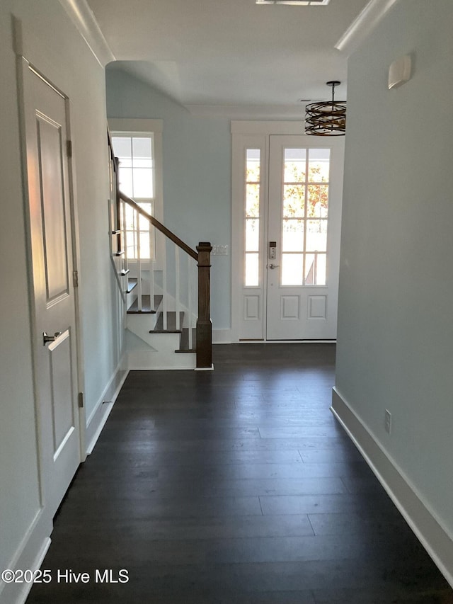 foyer entrance featuring dark wood-style floors, stairway, and baseboards