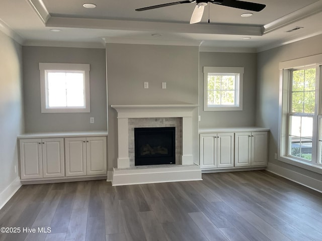 unfurnished living room featuring dark hardwood / wood-style floors, a healthy amount of sunlight, and a tray ceiling