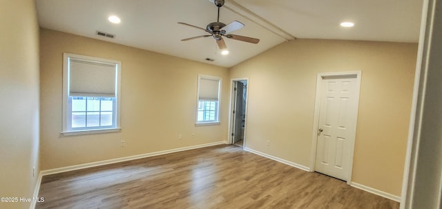 unfurnished bedroom with ceiling fan, wood-type flooring, multiple windows, and vaulted ceiling with beams