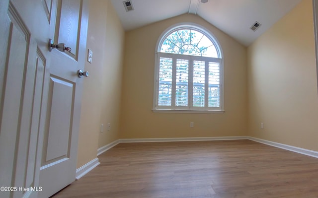 unfurnished room featuring lofted ceiling and light wood-type flooring