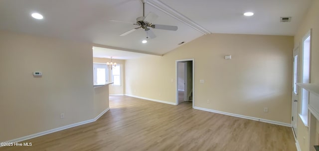 empty room featuring ceiling fan with notable chandelier, lofted ceiling with beams, and light hardwood / wood-style flooring