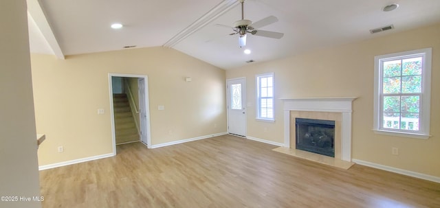 unfurnished living room featuring ceiling fan, a healthy amount of sunlight, vaulted ceiling with beams, and light hardwood / wood-style floors