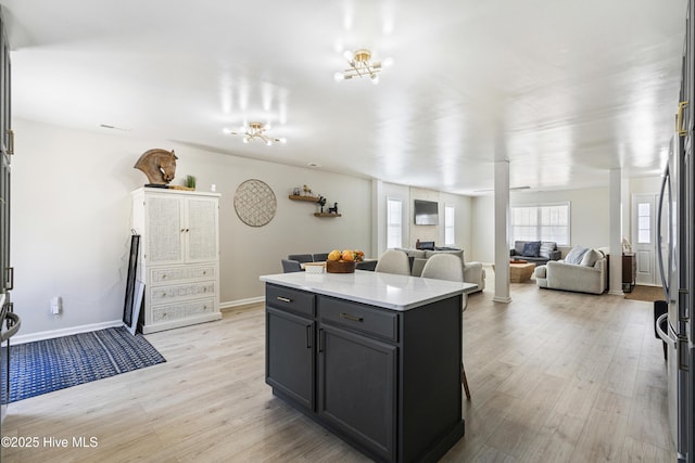 kitchen featuring a breakfast bar area, stainless steel fridge, a kitchen island, and light hardwood / wood-style flooring