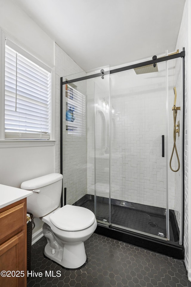 bathroom with vanity, a shower with shower door, tile patterned floors, and toilet