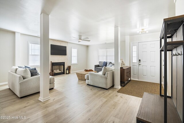 living room with ceiling fan, a fireplace, and light wood-type flooring