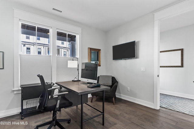 office area with dark wood-type flooring, visible vents, and baseboards