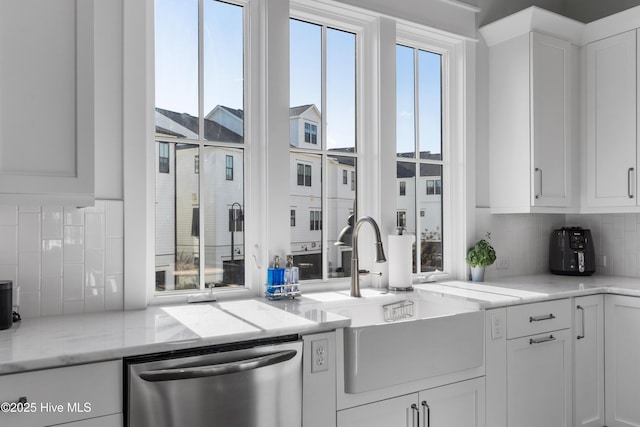 kitchen with sink, white cabinets, backsplash, stainless steel dishwasher, and light stone countertops