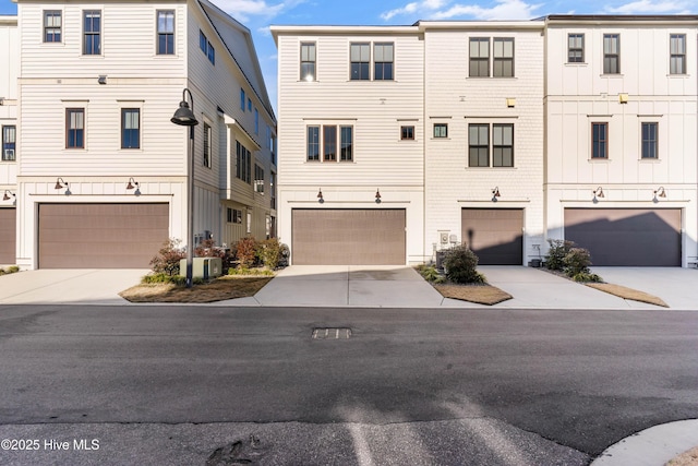 view of property with concrete driveway, a garage, and central AC