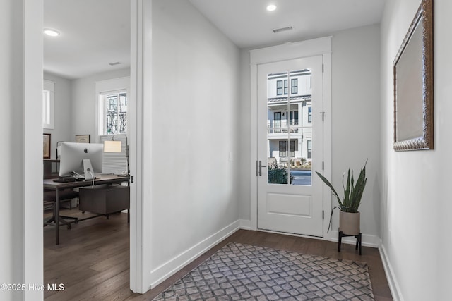 doorway to outside featuring visible vents, baseboards, and dark wood finished floors