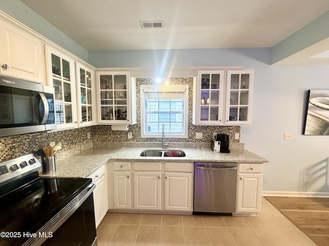 kitchen featuring appliances with stainless steel finishes, sink, white cabinets, and backsplash