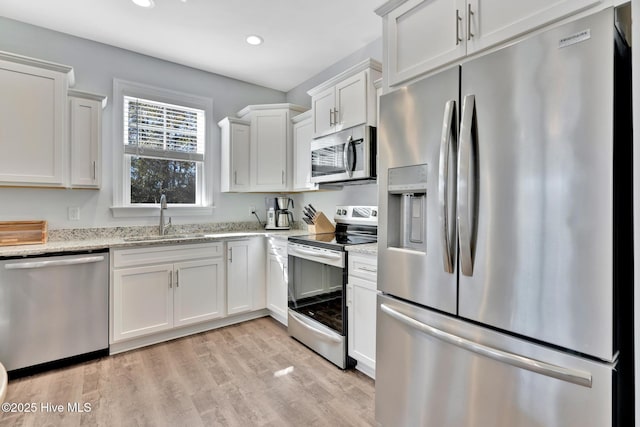 kitchen with white cabinetry, sink, stainless steel appliances, and light stone countertops