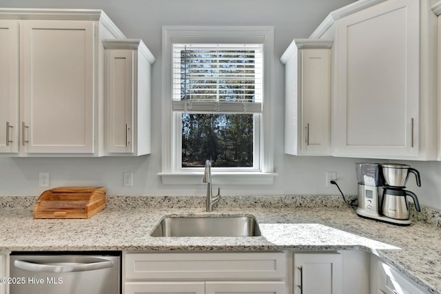 kitchen featuring stainless steel dishwasher, light stone countertops, sink, and white cabinets