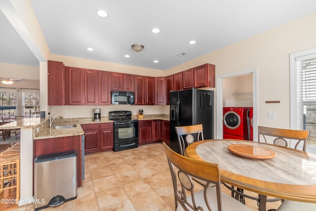 kitchen featuring black appliances, sink, kitchen peninsula, light stone countertops, and washer and clothes dryer