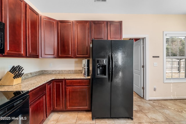 kitchen with light stone countertops, light tile patterned floors, and black appliances