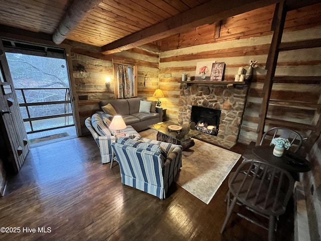 living room featuring wooden ceiling, dark wood-type flooring, beamed ceiling, a stone fireplace, and wood walls