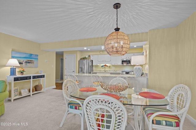 dining room with a chandelier, sink, and light carpet