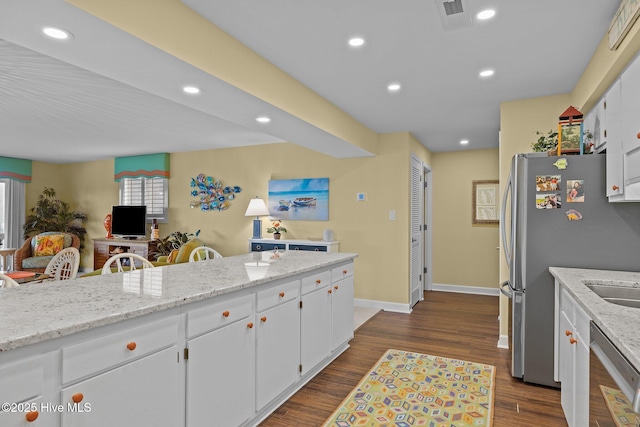 kitchen with dark wood-type flooring, sink, light stone counters, stainless steel appliances, and white cabinets