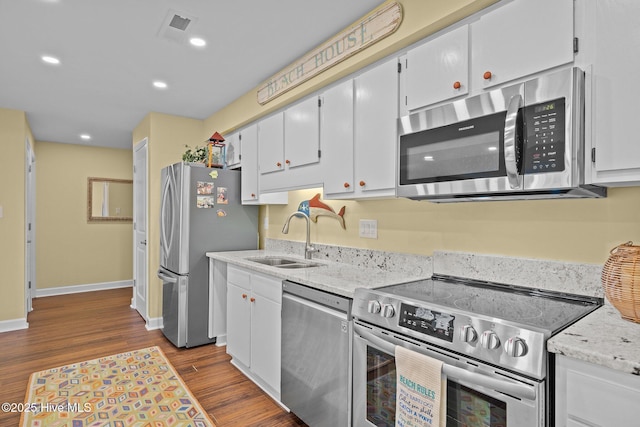 kitchen featuring sink, hardwood / wood-style flooring, appliances with stainless steel finishes, light stone counters, and white cabinets