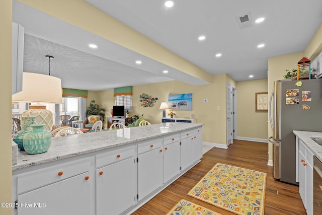 kitchen featuring hanging light fixtures, white cabinetry, wood-type flooring, and stainless steel refrigerator