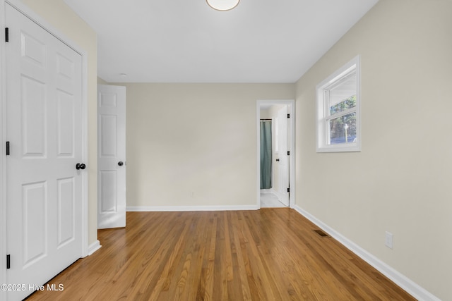 unfurnished bedroom featuring ensuite bathroom and light hardwood / wood-style floors