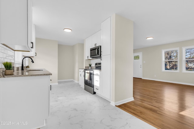 kitchen featuring white cabinetry, sink, decorative backsplash, light stone counters, and stainless steel appliances