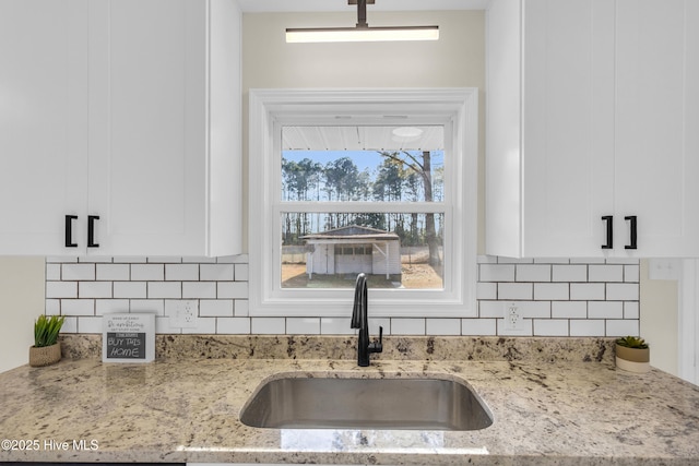 kitchen featuring white cabinetry, light stone countertops, sink, and decorative backsplash