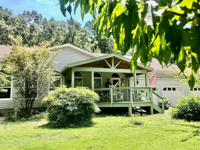 rear view of house with a garage, covered porch, and a lawn