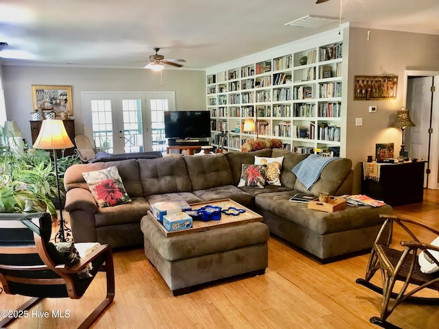 living area featuring light wood-style floors, ceiling fan, built in features, and crown molding