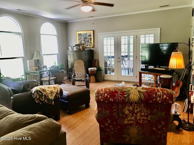 living area with visible vents, french doors, wood finished floors, and ornamental molding