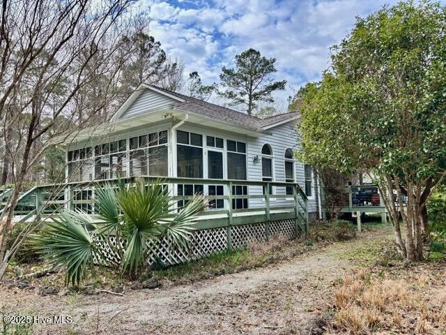 view of property exterior featuring a sunroom and a wooden deck