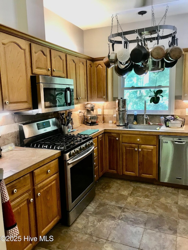 kitchen featuring tile counters, appliances with stainless steel finishes, backsplash, and a sink